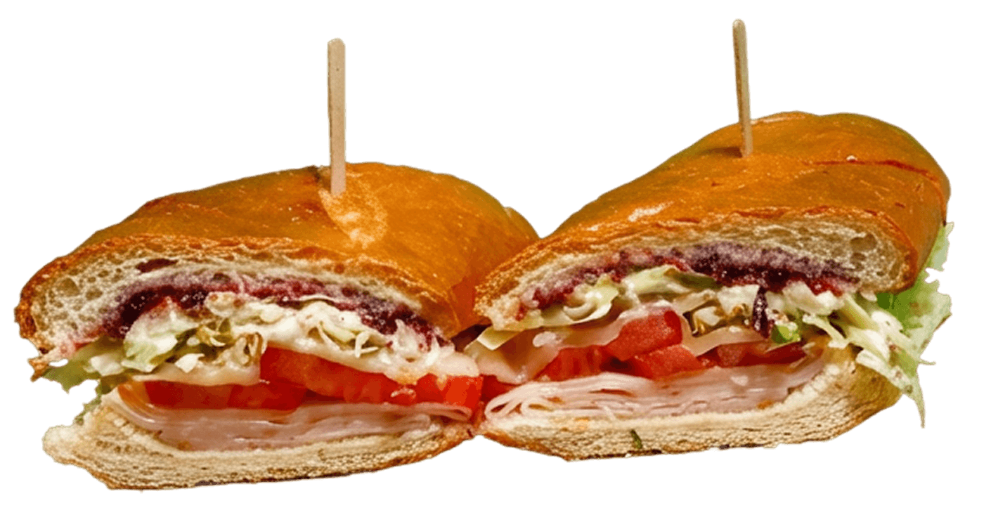 A long sub sandwich, cut into two halves, showcasing layers of deli meat, fresh green lettuce, and dark red/purple ingredients on a dark oblong plate.
