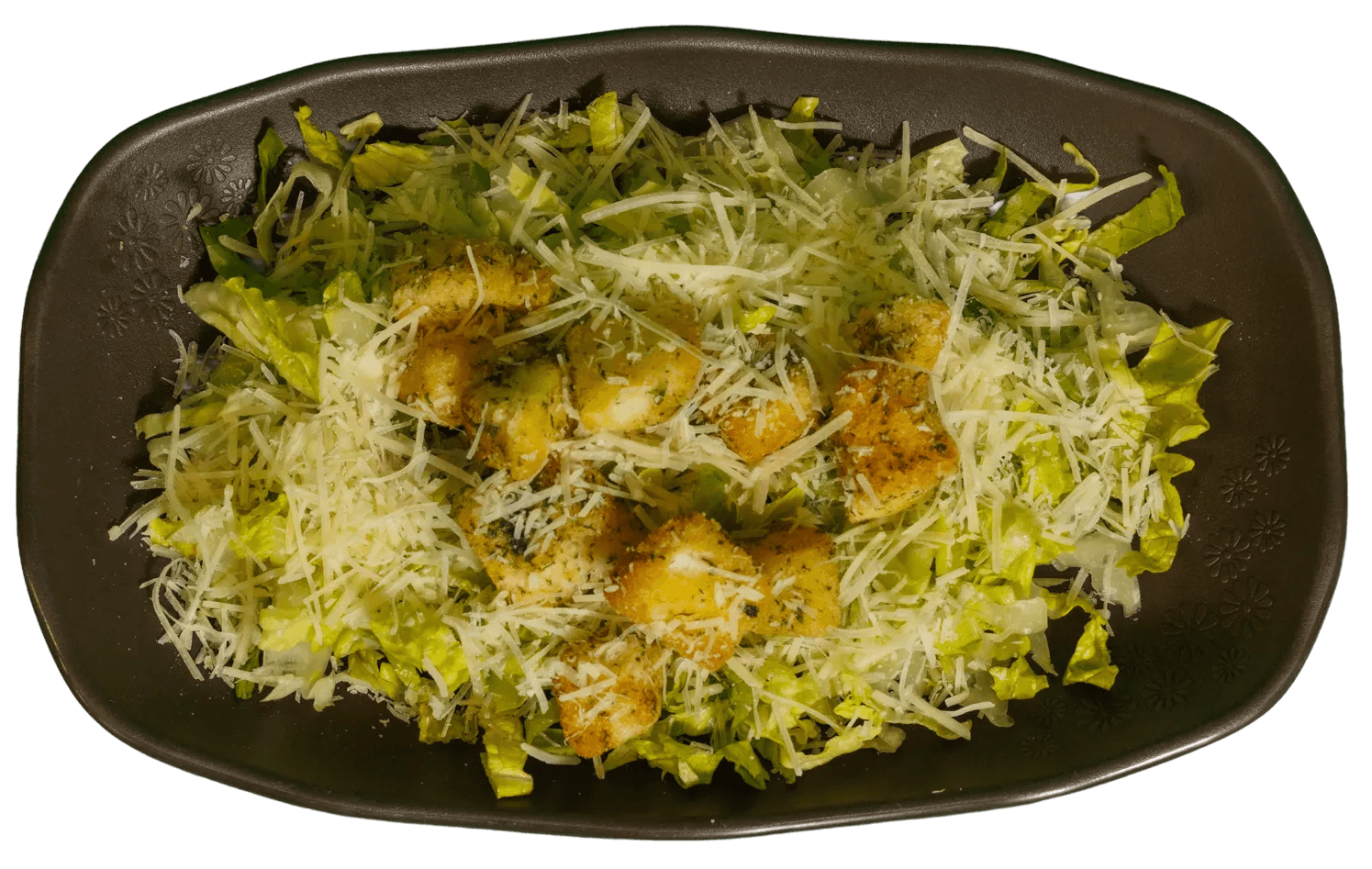 Caesar salad with chopped lettuce, shredded Parmesan cheese, and seasoned chicken pieces in a dark brown rectangular plate.