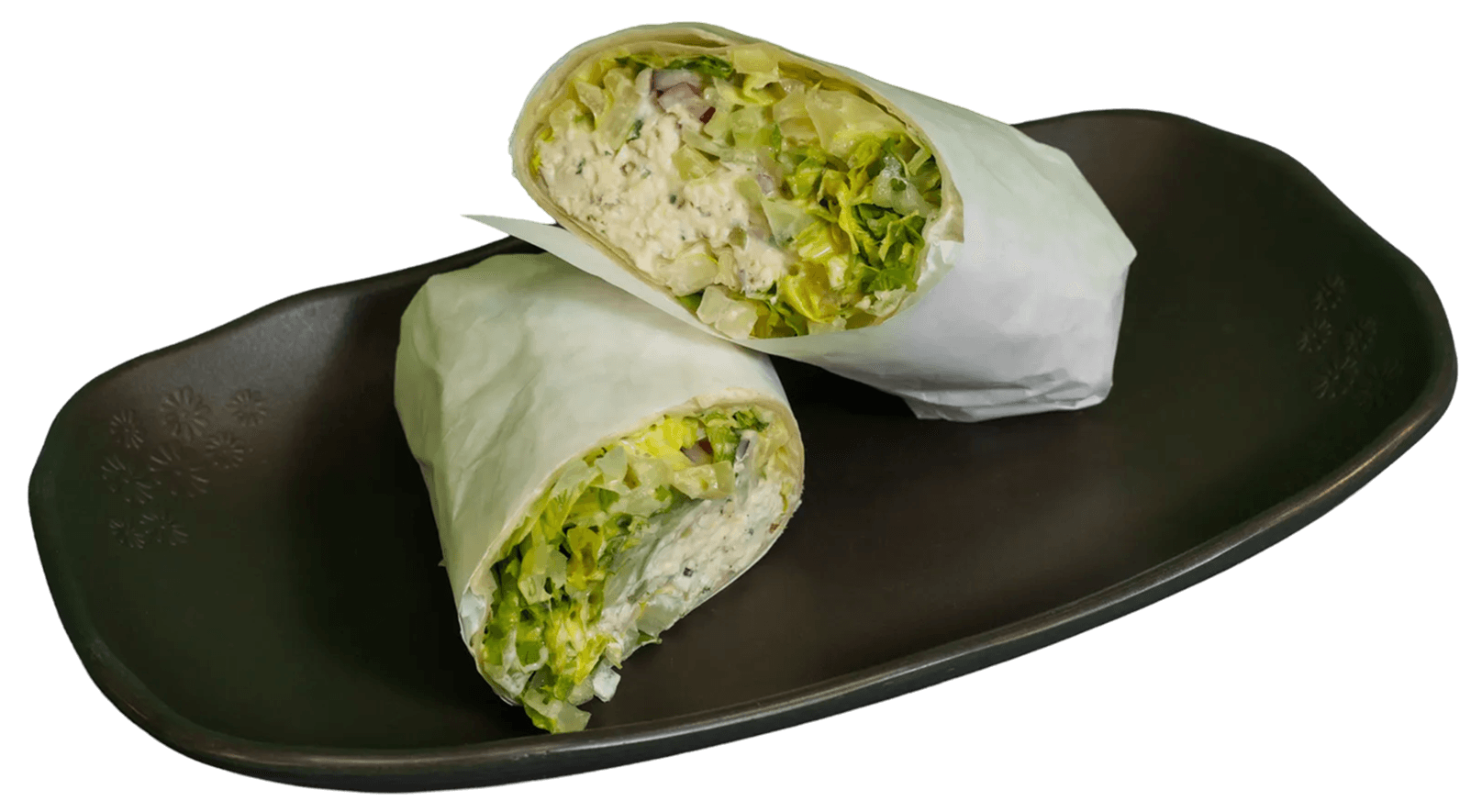 Two halves of a chicken salad wrap, revealing creamy filling, fresh lettuce, and red onion, are presented on a dark brown plate with a floral pattern.