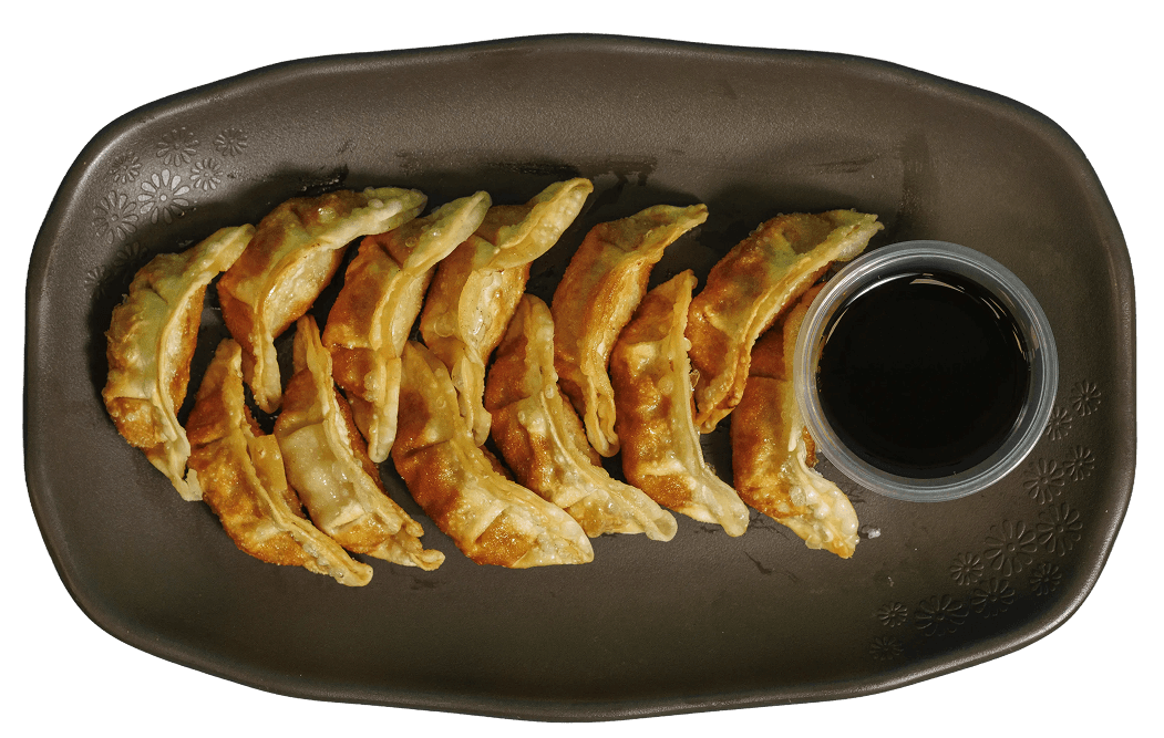 Golden-brown fried dumplings (gyoza) arranged in two rows on a dark brown plate with a side of soy sauce in a small plastic container.