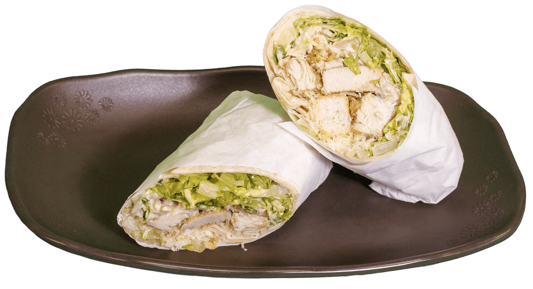 Two chicken Caesar wraps on a dark brown plate, one cut open to show chicken, lettuce, and dressing.